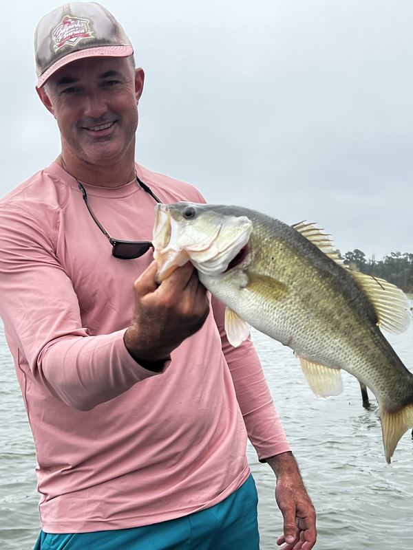 Close-up of Jeremiah holding a big largemouth bass on an overcast lake