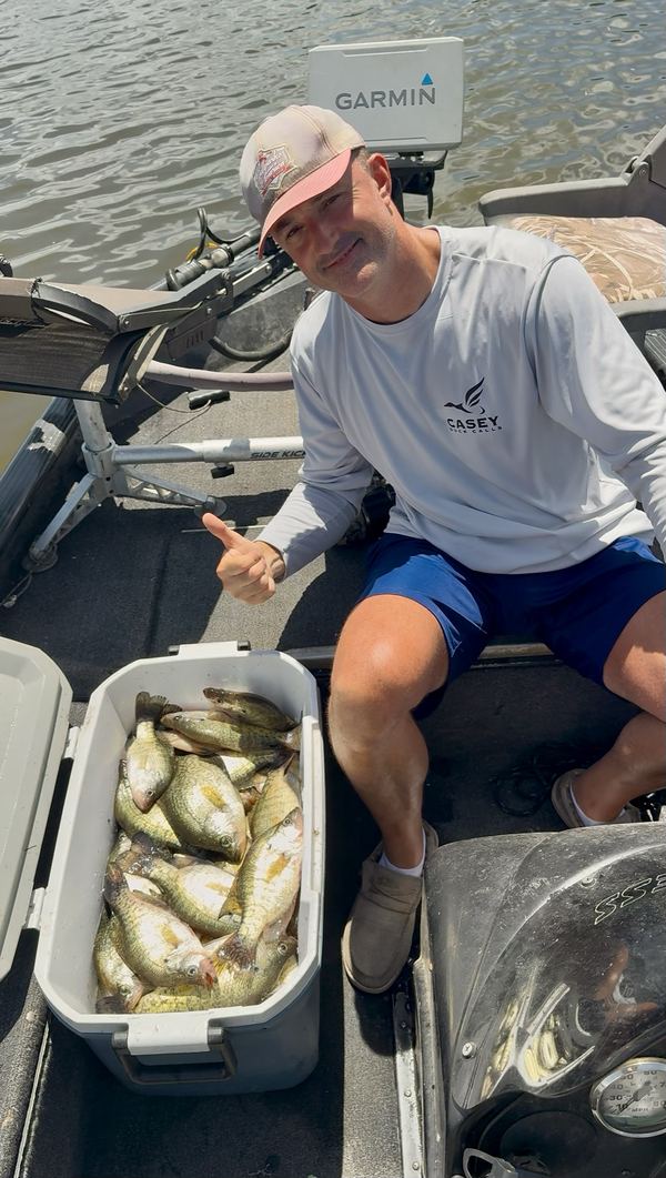Jeremiah giving a thumbs up in the boat next to a cooler of crappie